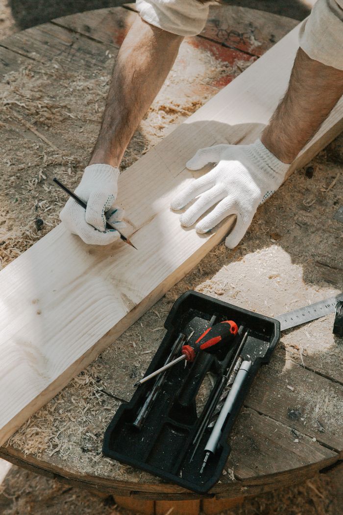 The Art of Drawing Readers In: Your attractive post title goes here Carpenter measuring and marking wood plank with precision tools and gloves.